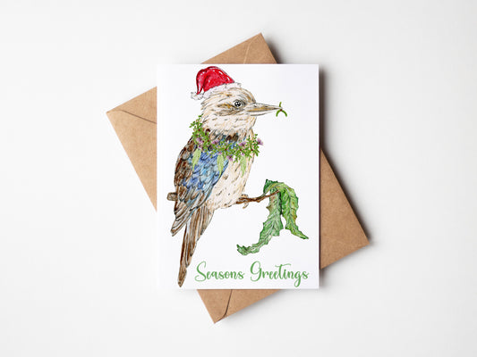 Greeting card with a kookaburra illustration and 'Seasons Greetings' text, accompanied by a brown envelope on a white background. Top End Christmas cards, Aussie Christmas cards, NT Christmas cards